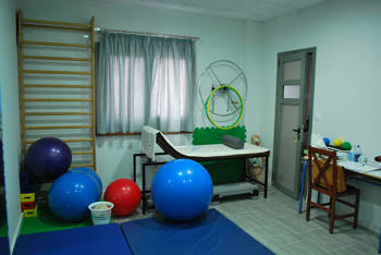 Photo showing a room with a therapeutic bed, exercise equipment and a small desk